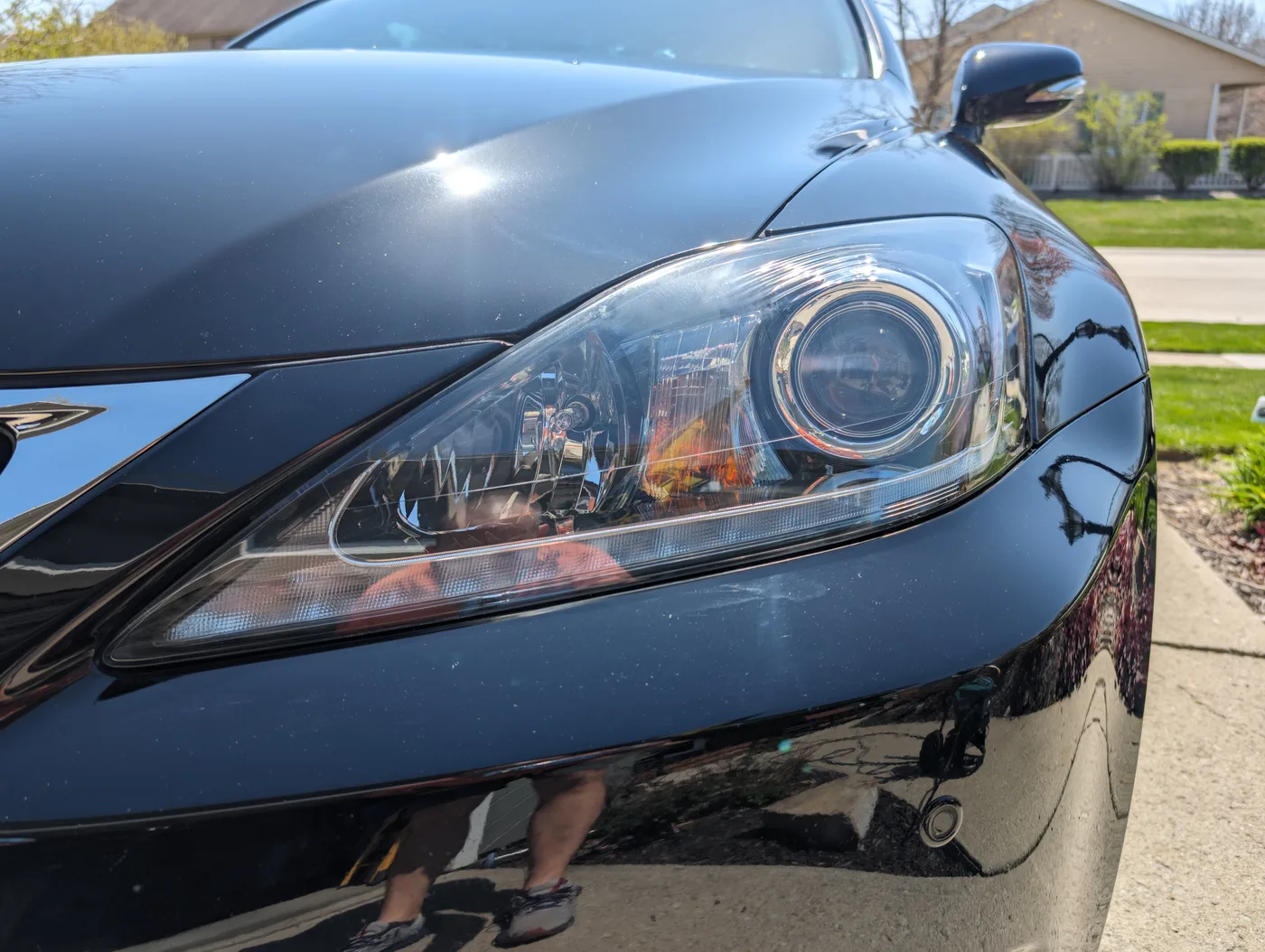 The same black Lexus IS in daylight after paint correction, the hood reflecting cleanly